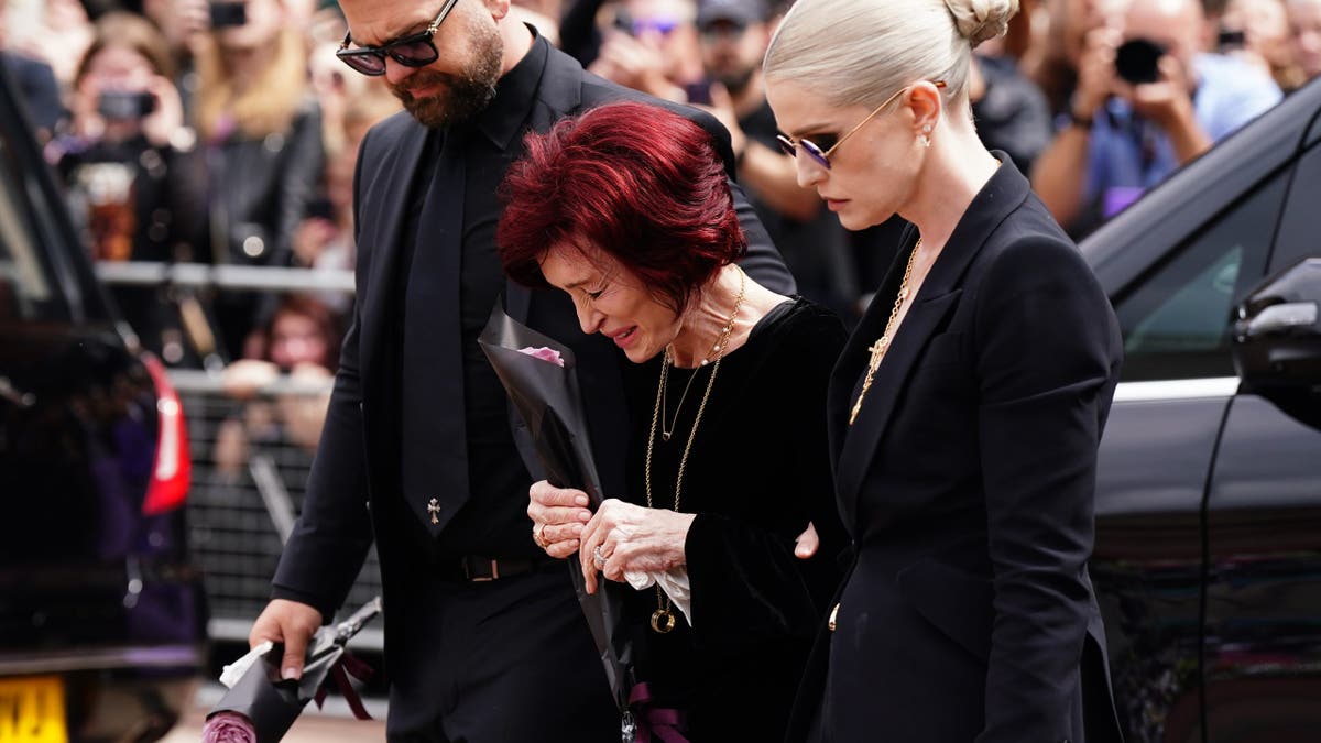 Sharon Osbourne crying at Ozzy Osbourne's funeral, surrounded by children Jack and Kelly