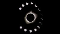during a total solar eclipse the sun appears as a dark spot with bright white light beaming out from behind. A series of phases surround the main eclipse image, showing the moon take a progressively bigger "bite" out of the sun.