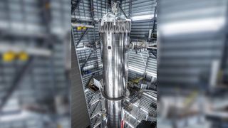 a tall silver rocket upright in a hangar