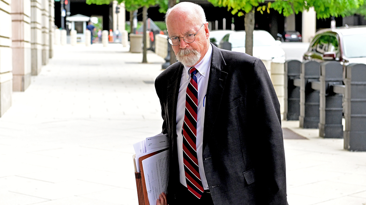 John Durham walks outside while holding papers