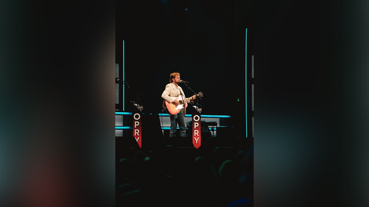 Conner Smith with his guitar performing at the grand ole opry